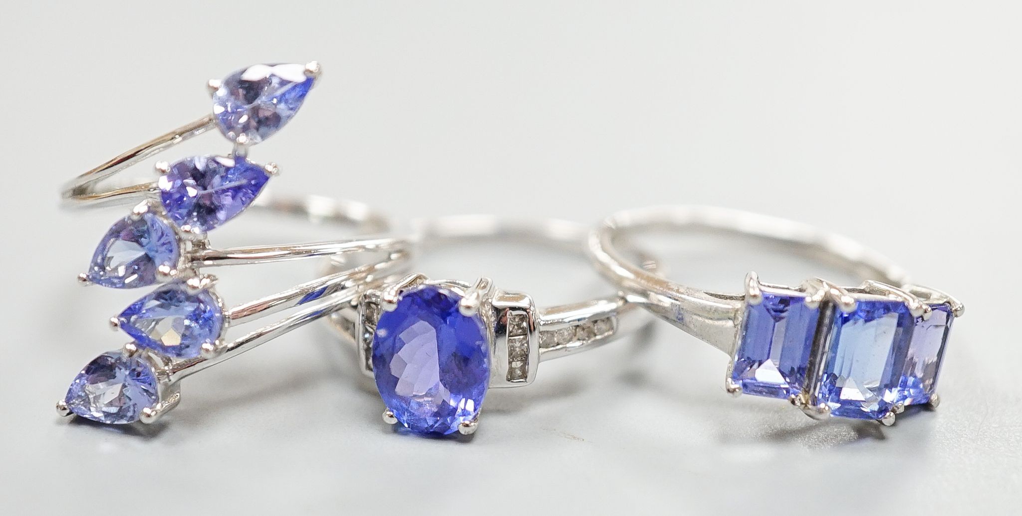 Three assorted modern 9ct white gold and tanzanite set dress rings, gross weight 8.6 grams.